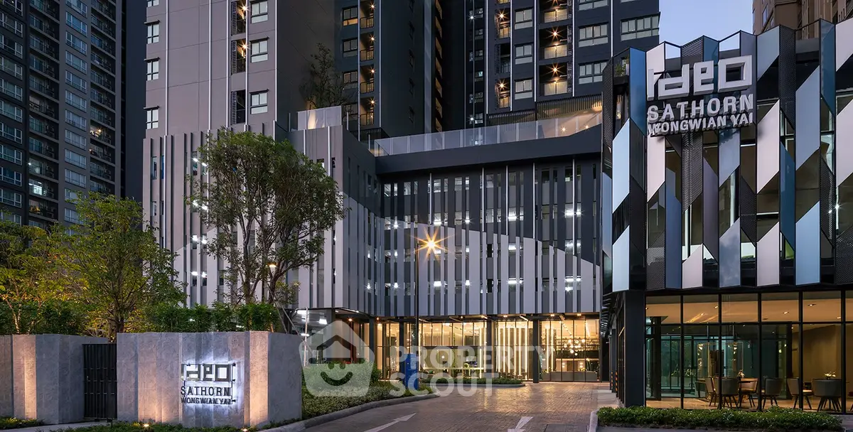 Modern high-rise building exterior with sleek design and lush greenery at dusk.