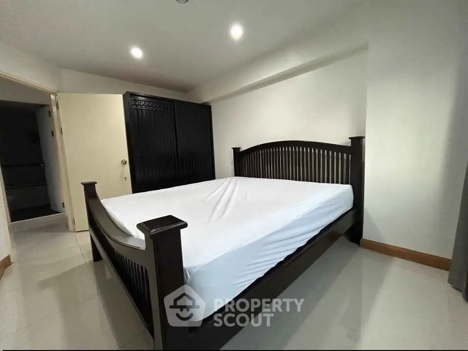 Spacious bedroom with elegant dark wood bed frame and ample natural light.
