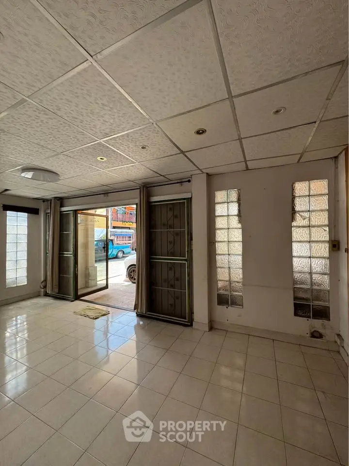 Spacious living room with large windows and tiled flooring, perfect for natural light.