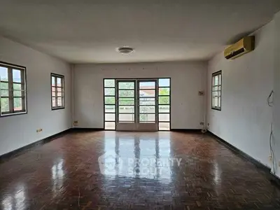 Spacious empty living room with parquet flooring and large windows