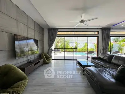 Spacious modern living room with pool view, large TV, and stylish furniture, perfect for relaxation.