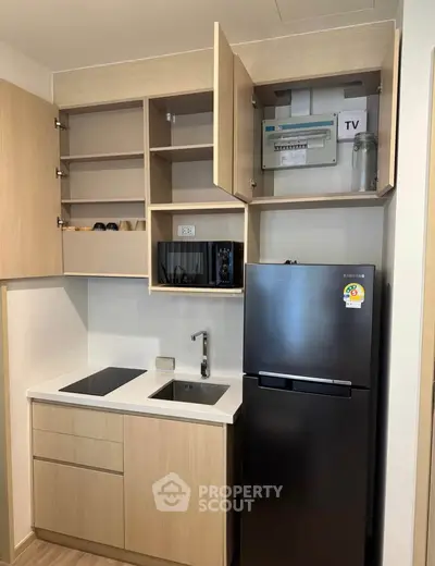 Modern compact kitchen with sleek appliances and open shelving in a stylish apartment.