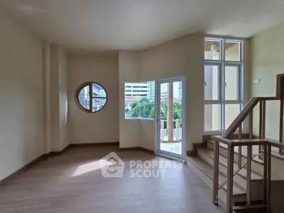 Spacious living room with unique circular window and balcony access in modern apartment.