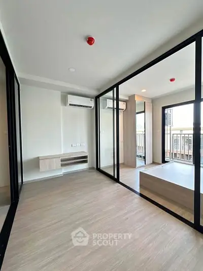 Modern apartment interior with glass partitions and balcony view, featuring sleek air conditioning units.