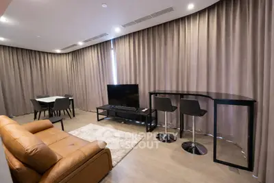 Modern living room with leather sofa, TV, and dining area in open layout.