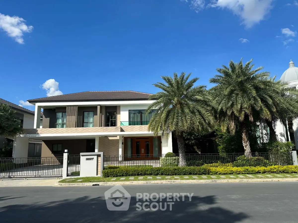 Luxurious modern house with palm trees and clear blue sky, showcasing elegant architecture and curb appeal.