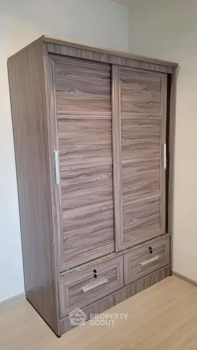 Modern wooden wardrobe with sliding doors in a minimalist bedroom setting.