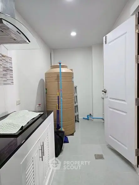 Utility room with water tank and modern appliances in a residential property.