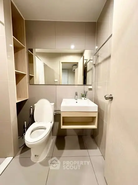 Modern bathroom with sleek fixtures and large mirror in contemporary apartment.