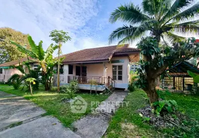 Charming tropical bungalow with lush garden and palm trees, perfect for serene living.