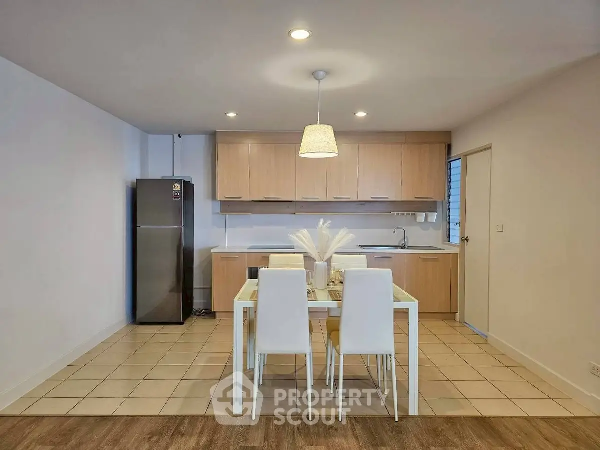 Modern kitchen with dining area, featuring sleek cabinetry and contemporary lighting.