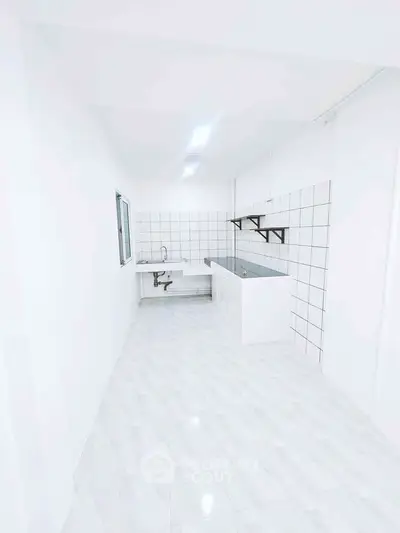 Bright minimalist kitchen with white tiles and open shelving, perfect for modern living.