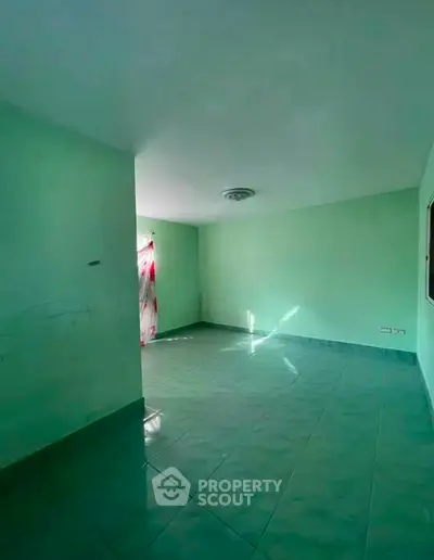 Spacious empty room with green walls and tiled floor, ideal for customization.