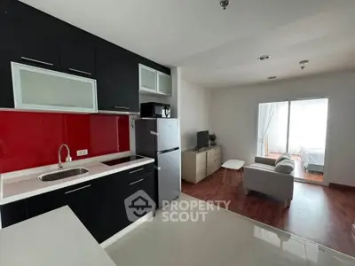 Modern open-layout kitchen and living room with sleek black cabinets and bright red backsplash.