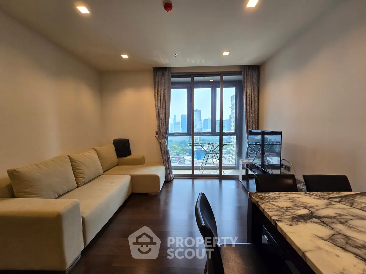 Spacious living room with modern furniture and city view balcony, perfect for urban living.