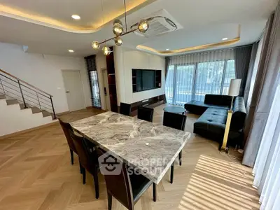Modern living room with stylish dining area and elegant lighting, featuring a marble table and cozy seating.