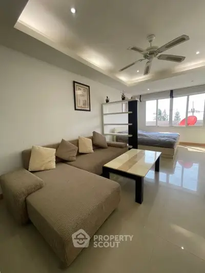Spacious studio apartment with modern furnishings and large windows offering natural light.