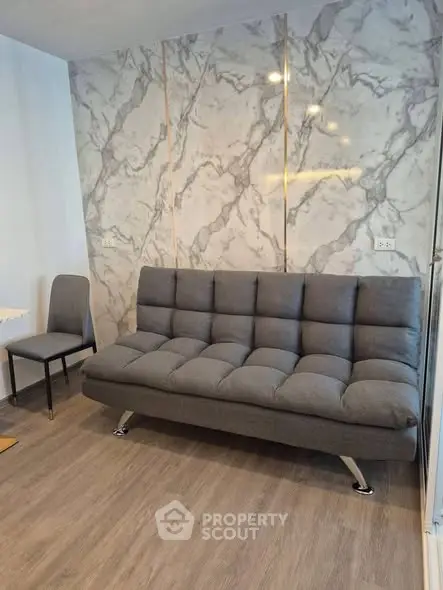 Modern living room with stylish gray sofa and marble accent wall, perfect for contemporary urban living.