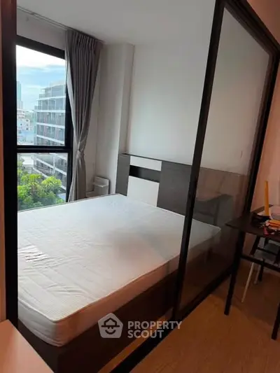 Modern bedroom with large window and city view, featuring sleek design and natural light.