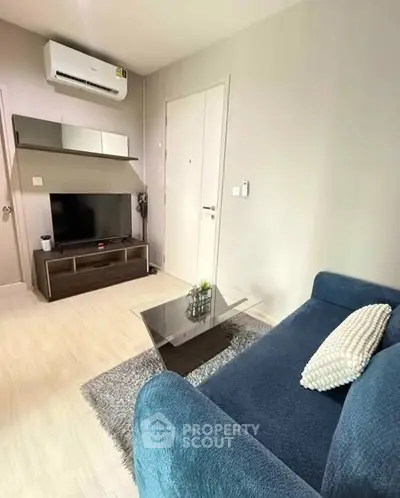 Modern living room with blue sofa, TV, and air conditioning in a cozy apartment.