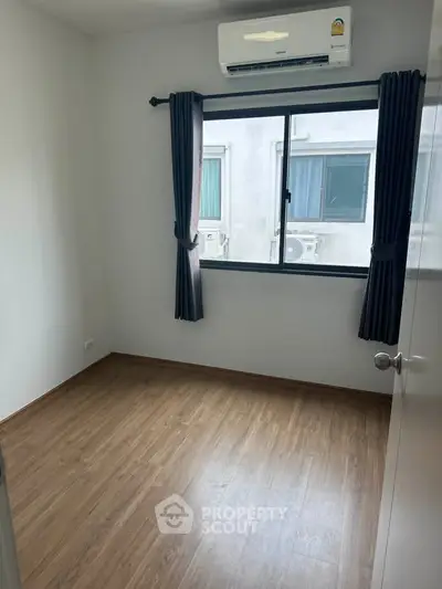 Bright bedroom with wooden flooring and air conditioning, perfect for a cozy living space.