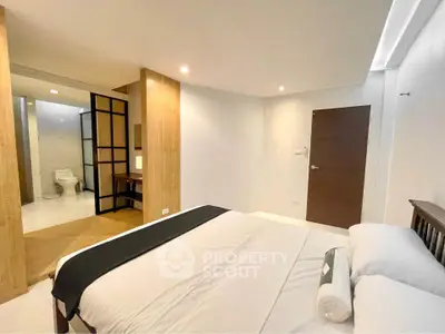 Spacious modern bedroom with ensuite bathroom and elegant wooden accents.