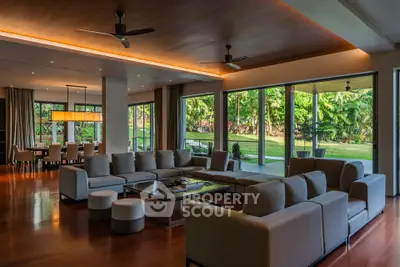 Luxurious open-plan living room with garden view, featuring modern furniture and elegant lighting.