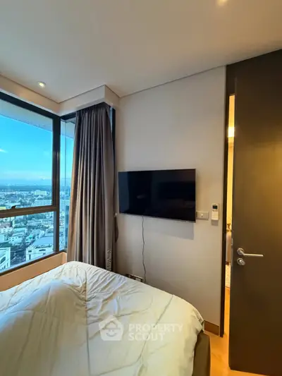 Modern bedroom with city view and wall-mounted TV in high-rise apartment