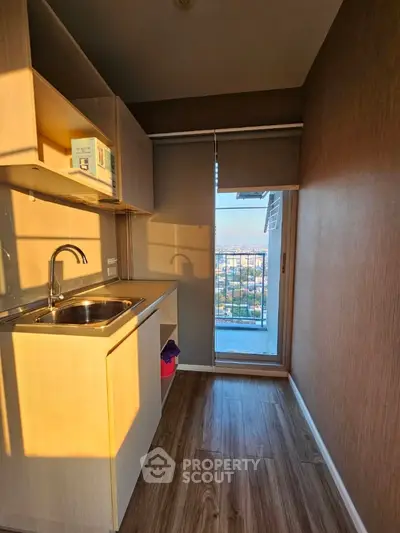 Sunlit compact kitchen with modern fittings, ample storage, and a charming balcony view, ideal for urban living in a cozy space.