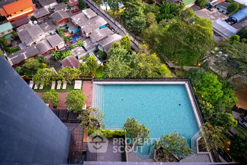 Stunning aerial view of luxurious rooftop pool surrounded by lush greenery in urban setting.
