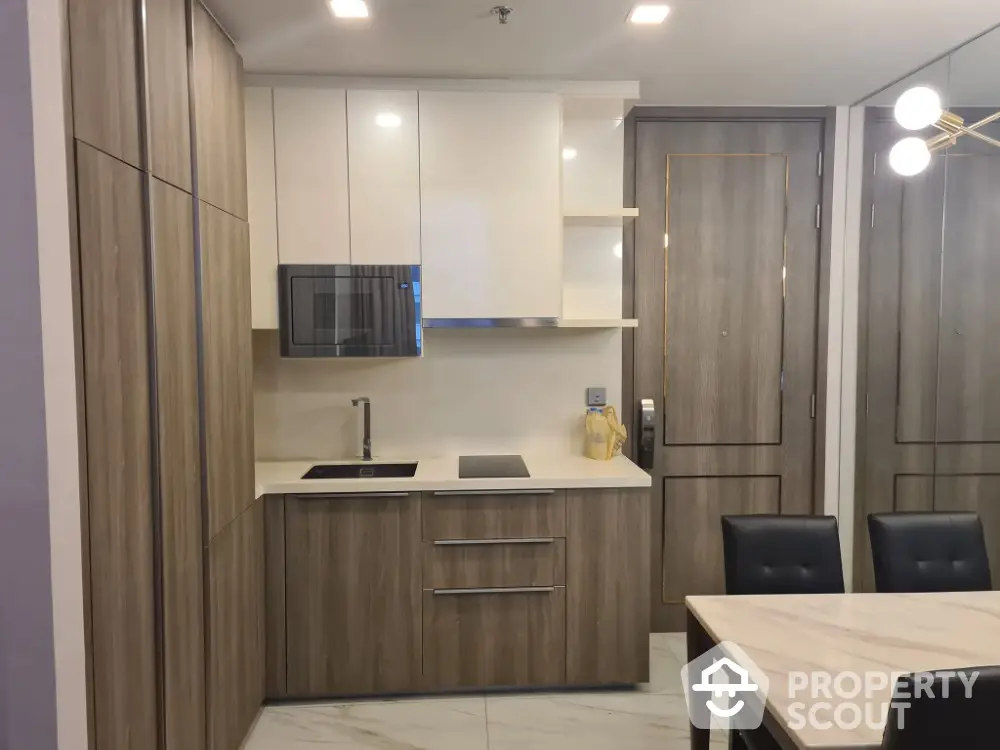 Modern kitchen with sleek cabinetry and dining area in contemporary apartment