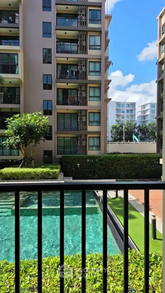 Modern apartment building with pool view and lush greenery, perfect for urban living.