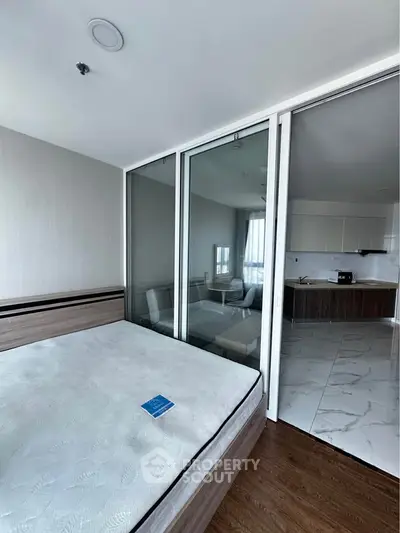 Modern bedroom with glass partition and view into sleek kitchen area
