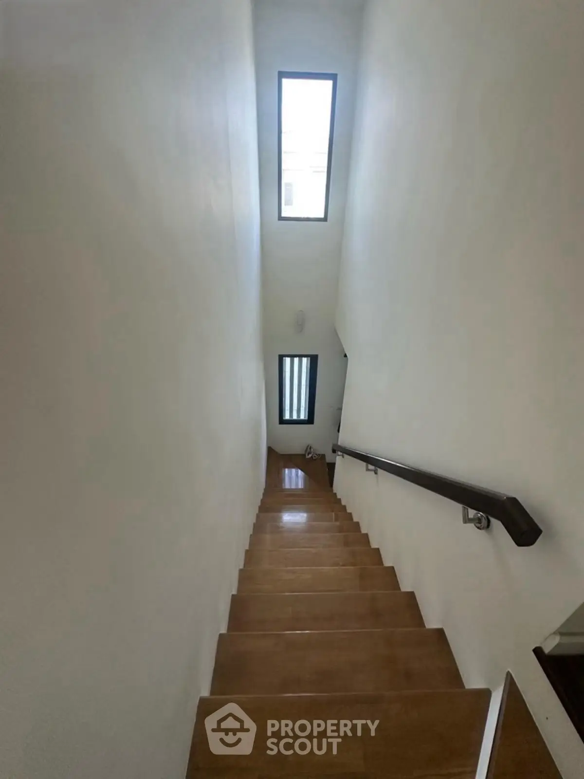 Modern staircase with wooden steps and skylight in a minimalist home