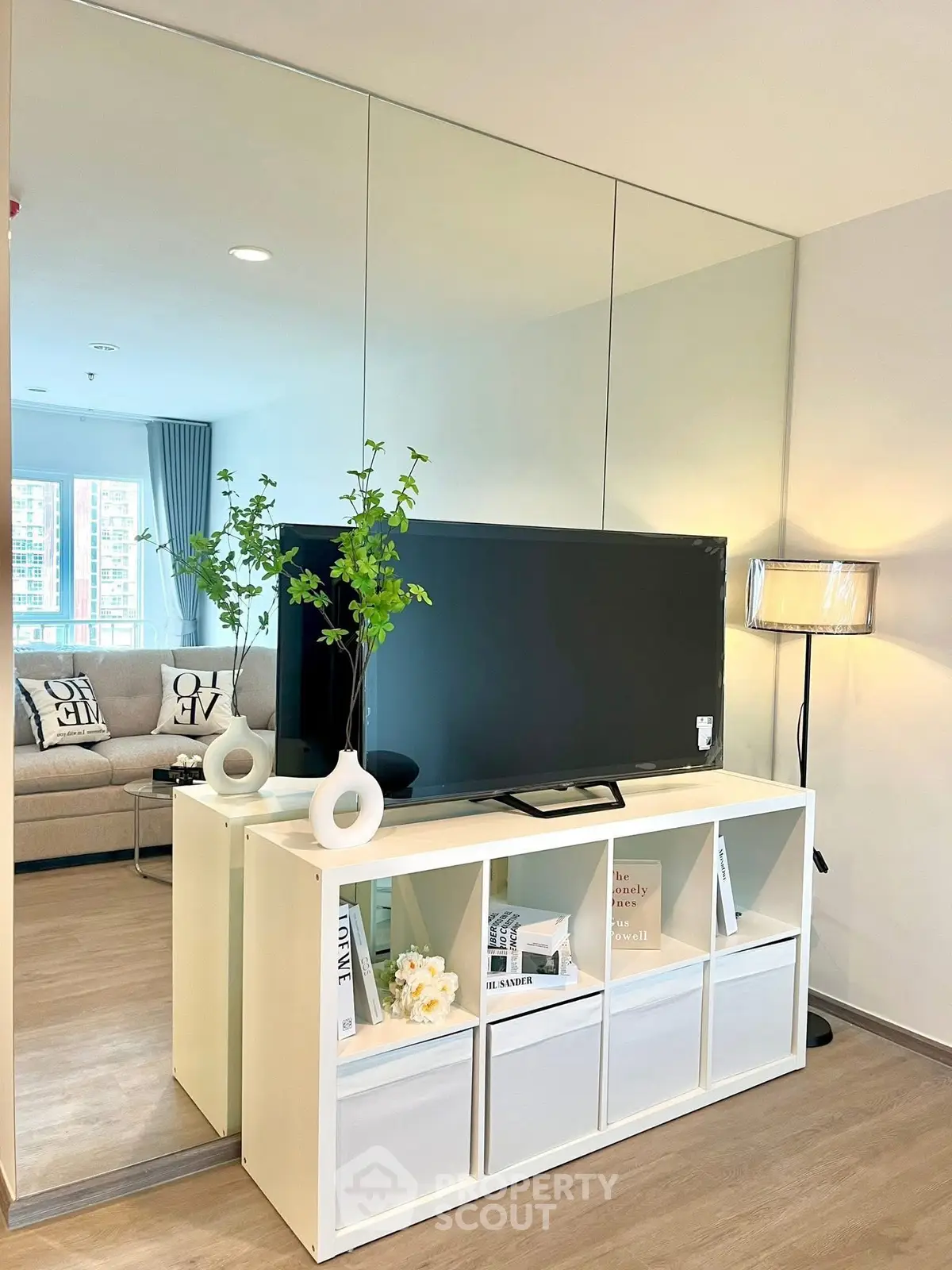 Modern living room with sleek TV stand and mirrored wall, enhancing space and style.