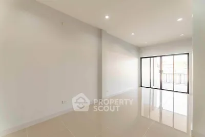 Spacious empty living room with large windows and glossy tiled floors.