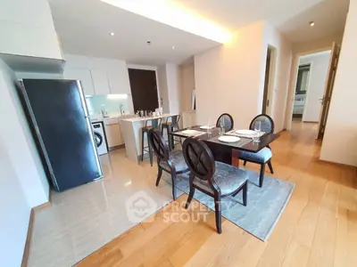 Modern open-layout kitchen and dining area with sleek appliances and elegant dining set.