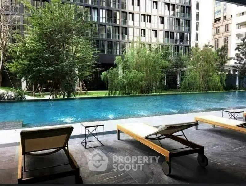 Luxurious poolside view with modern loungers and lush greenery in upscale residential complex.