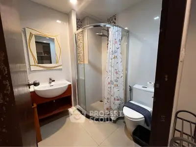 Modern bathroom with shower, sink, and toilet in a stylish real estate property.