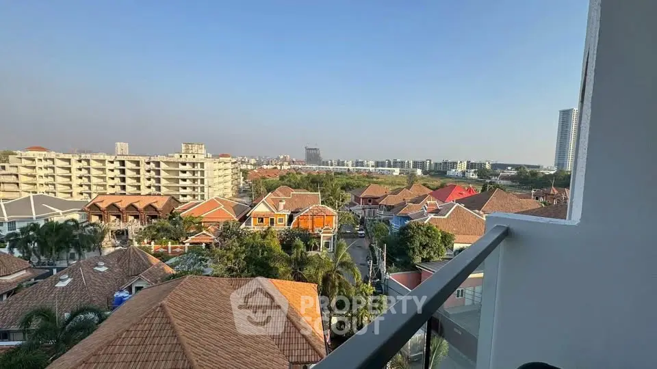 Stunning panoramic view from a high-rise balcony overlooking vibrant rooftops and cityscape.