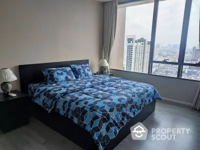 Spacious bedroom with large windows offering panoramic city views, modern furnishings, and ample natural light.