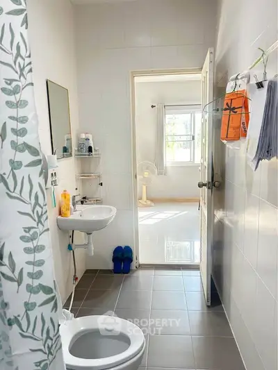 Bright bathroom with modern fixtures and view into sunlit room