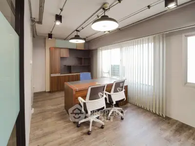 Modern office space with wooden flooring and large windows offering natural light.