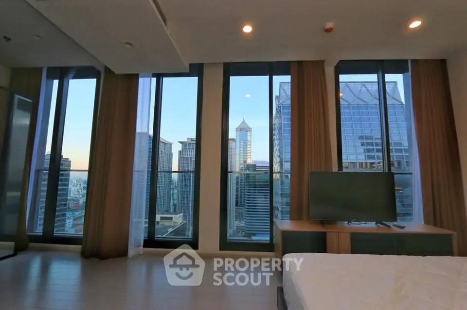 Luxurious bedroom with stunning city skyline view and floor-to-ceiling windows.
