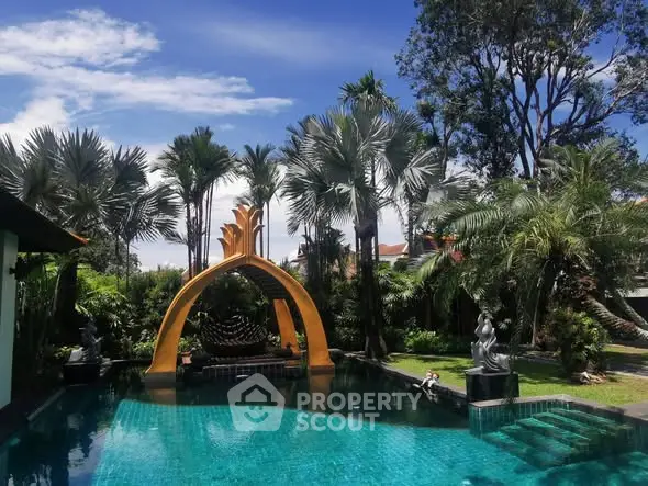 Luxurious tropical pool area with palm trees and artistic archway, perfect for relaxation and leisure.