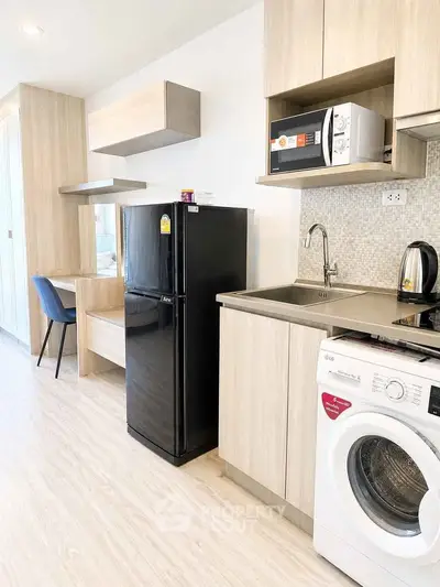 Modern kitchen with sleek appliances and light wood cabinetry in a stylish apartment.