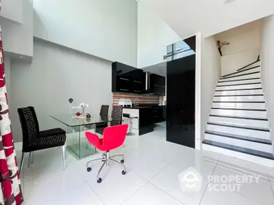 Modern open-plan kitchen and dining area with sleek black cabinetry and stylish decor.