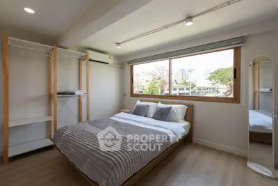 Modern bedroom with large window and minimalist decor in urban apartment