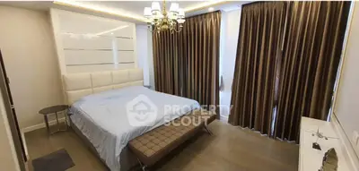 Luxurious bedroom with elegant decor, featuring a plush bed, stylish chandelier, and floor-to-ceiling curtains.
