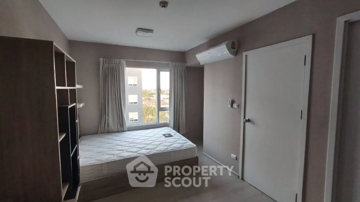 Cozy bedroom with natural light, featuring a comfortable bed and modern air conditioning unit.